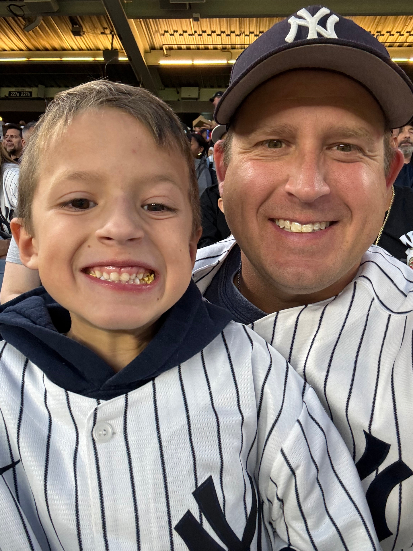 Matt smiling with his son at a Yankees game.