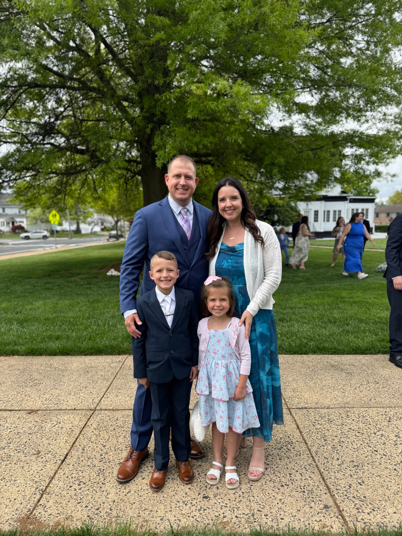 Matt with his family dressed up outdoors under a large tree.